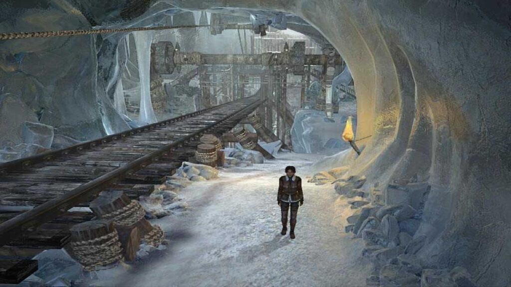 Kate Walker explores an icy tunnel with a wooden railway track and machinery in Syberia II.